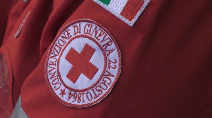 La Croce Rossa misura la temperatura alle persone in coda e consegna guanti e mascherine