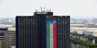 Cinque volti di dipendenti mantovani di Poste sulla maxi bandiera a sostegno della Nazionale che sventola sulla sede di Roma
