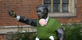 Fasce portabebè sulle statue: la protesta creativa dei papà che vogliono un congedo più lungo